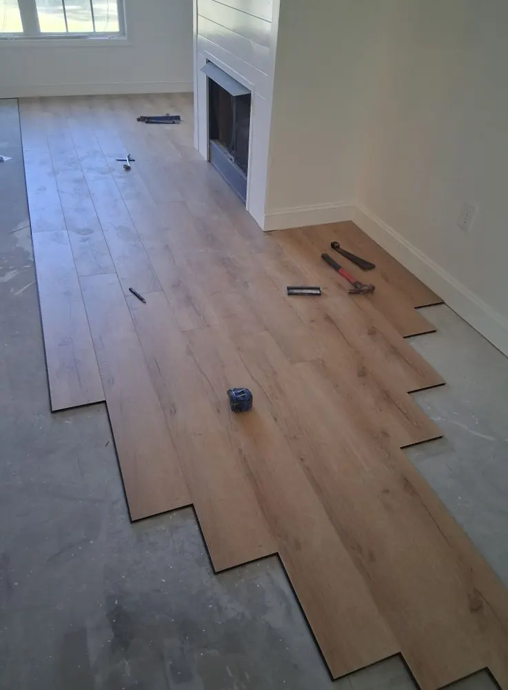 Luxury vinyl plank flooring being installed in a living room with a fireplace in Dunham Marsh, Richmond Hill GA