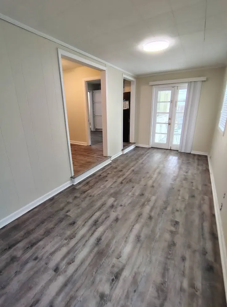Gray luxury vinyl plank flooring in a sunroom with French doors in Buckhead, Richmond Hill GA