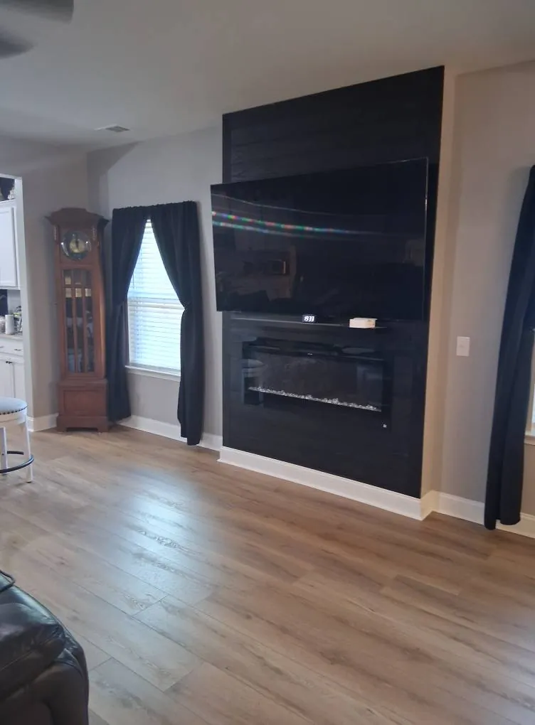 Luxury vinyl plank flooring in a finished living room with fireplace wall in Southbridge, Savannah GA