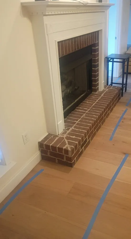 Wide-plank engineered wood flooring glued down around a brick fireplace in Irongate, Statesboro GA