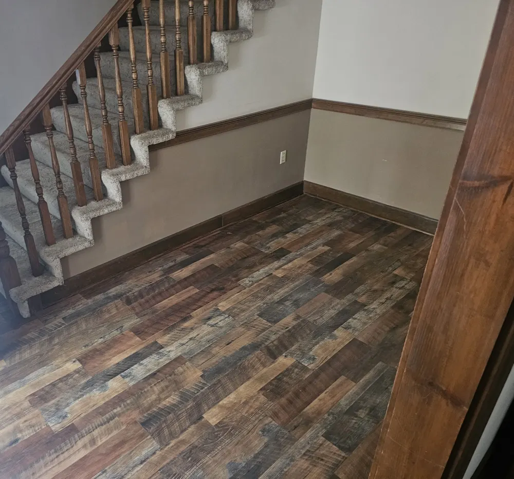 Rustic multi-tone luxury vinyl plank flooring in a front entry by the stairs in Old Mill, Statesboro GA